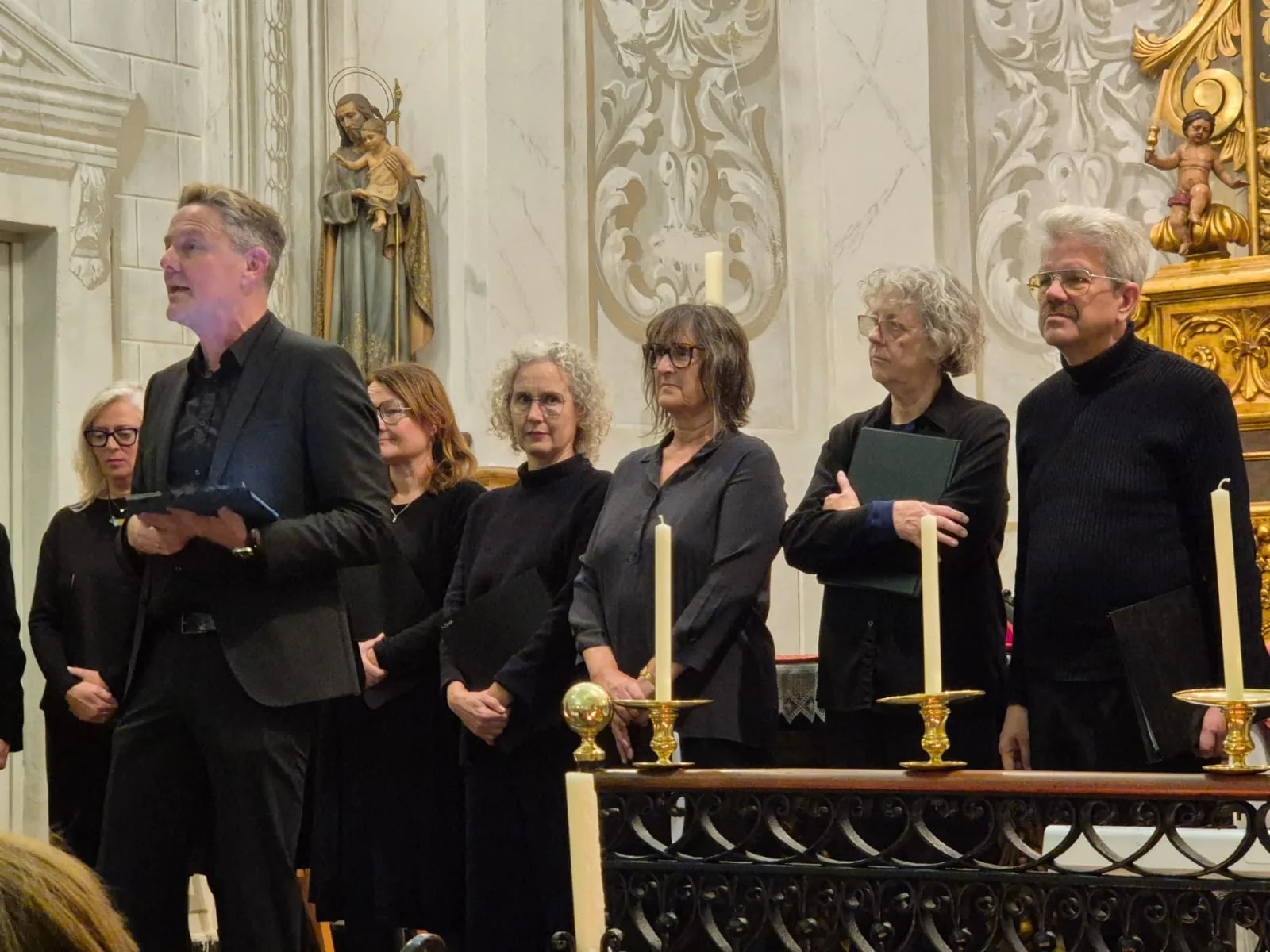 Cantaires de Camerata Sitges darrere la barana de l’altar durant un concert