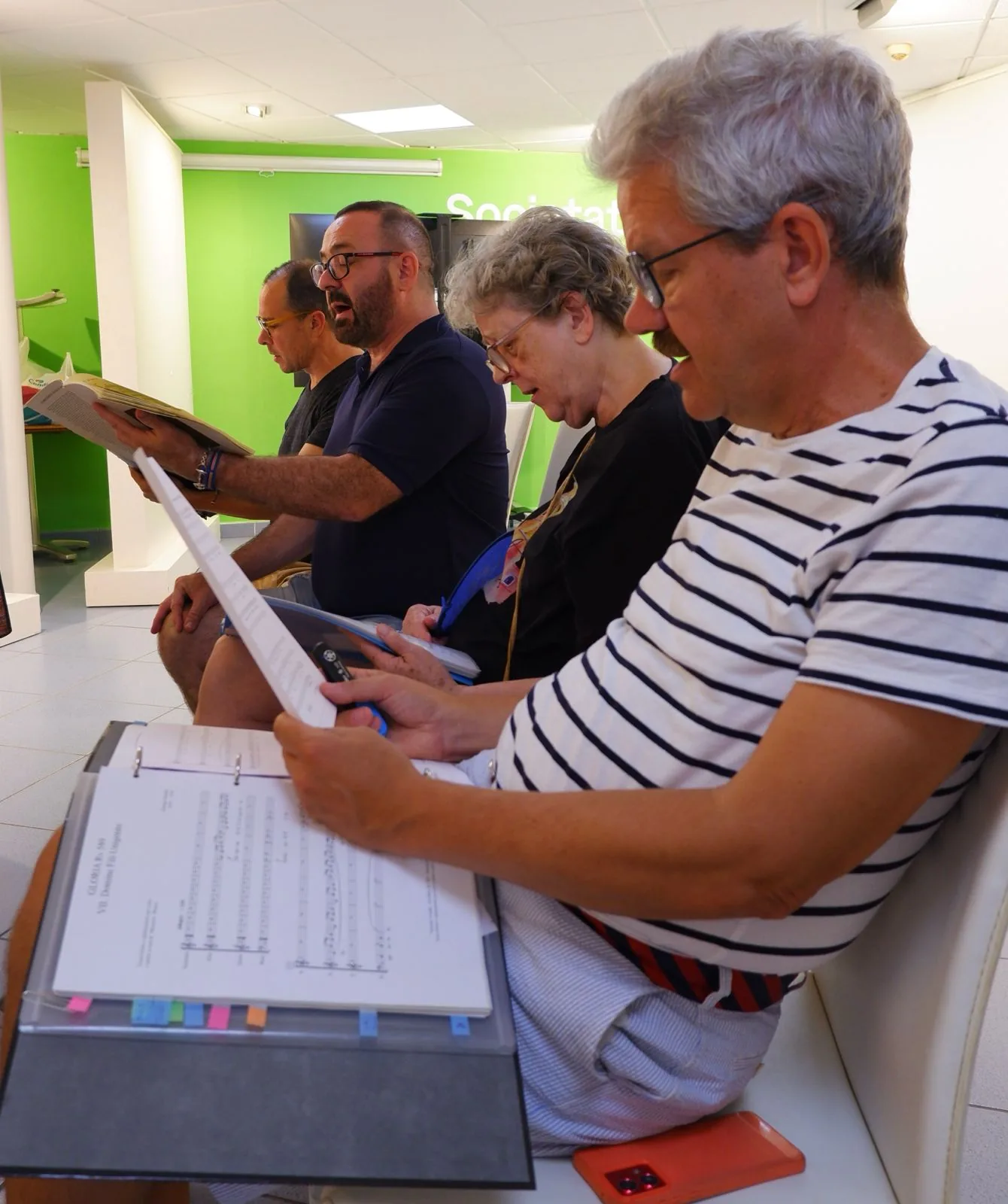 Cantaires llegint partitures durant un assaig